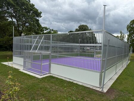 Bild des neuen Soccercourts mit lila Boden und einer Begrenzung aus Stahl auf einer grünen Wiese