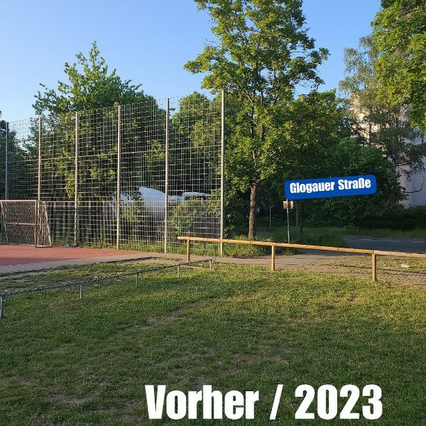 Der Hartplatz vor der Zaunschließung. Man sieht ein Stück Rasen und ein Fußballtor, hinter dem nur ein Stück Zaun angebracht ist.